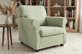 Housse extensible vert sauge sur fauteuil club dans un salon moderne avec parquet en chêne blanchi et décoration naturelle
