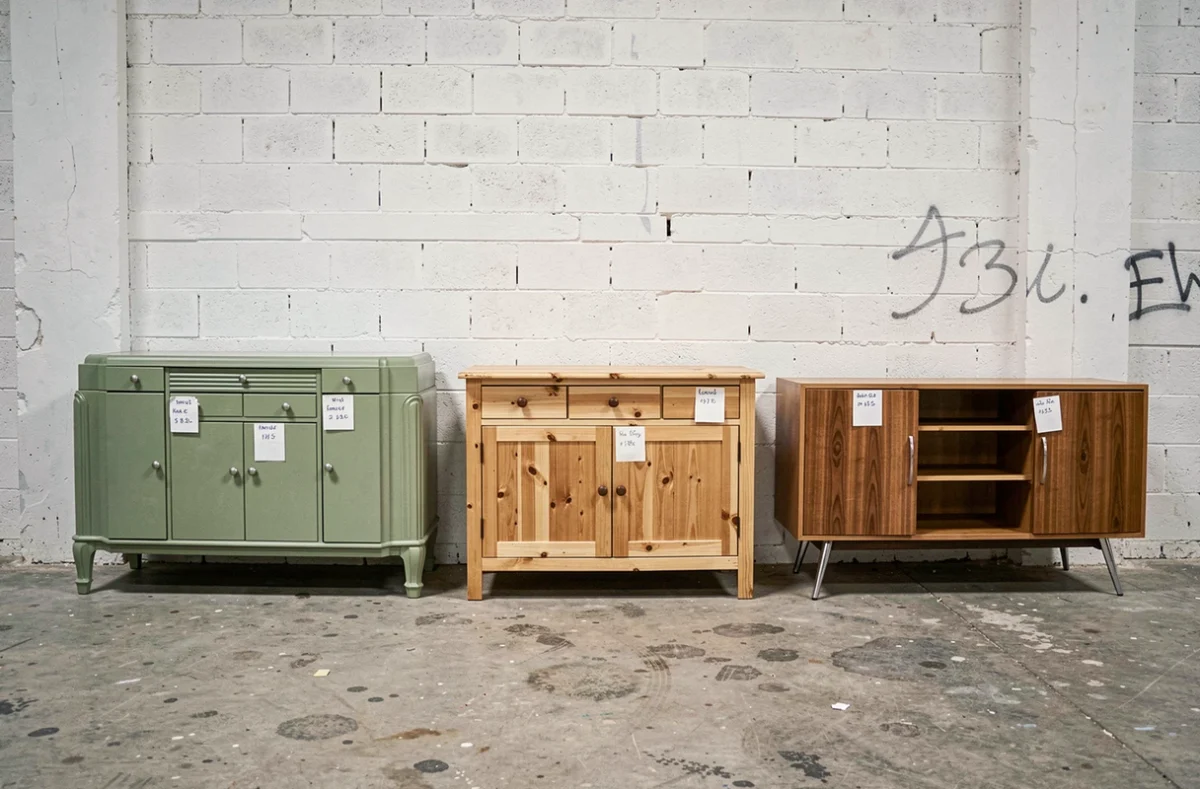 Trois buffets d'occasion exposés dans un entrepôt Emmaüs, modèles Art Déco, rustique et années 70