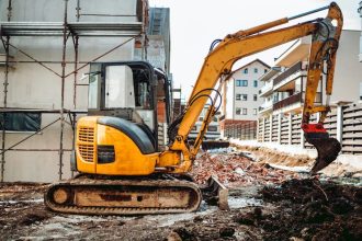 Mini pelle jaune en train de creuser une fondation pour une clôture